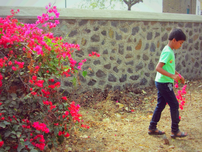 An Indian kid walks off with pretty flowers.